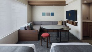A modern hotel room with a sofa, two single beds, a round table, and a TV. - Premium MONday OSAKA SHINSAIBASHI (Osaka)