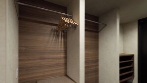 A walk-in closet with wooden paneling, a metal rod for hanging clothes, and a built-in shelf with a mesh bottom. - Premium MONday OSAKA SHINSAIBASHI (Osaka)