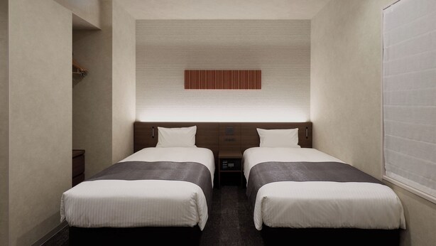 A hotel room with two beds, a small bedside table, a wall-mounted control panel, and a window with blinds. - Premium MONday OSAKA SHINSAIBASHI (Osaka)