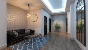 A modern interior with a black leather sofa, a patterned rug, a ceiling light, and a clock on the wall. - Cannon Street Serviced Apartments (London)