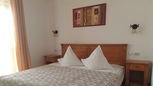A neatly made bed with a patterned bedspread, wooden headboard, and two bedside tables with lamps. - Casa Magica (Bușteni)