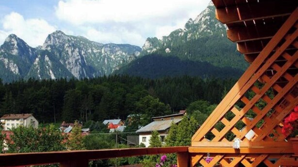 A mountain view with a wooden deck and a house in the foreground. - Casa Magica (Bușteni)