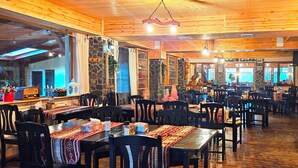 A restaurant with wooden interior, stone walls, and multiple tables and chairs. - Casa Magica (Bușteni)