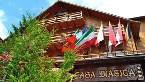 A wooden building with a sign reading 'CASA MAGICA' and multiple flags. - Casa Magica (Bușteni)