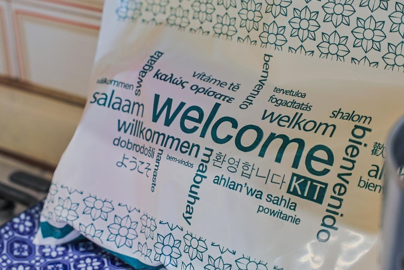 A welcome bag with multilingual text and a floral pattern.