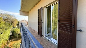 Ein Balkon mit Blick auf einen Garten und ein Gebäude gegenüber.