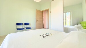 Ein Hotelzimmer mit einem Bett, zwei Sesseln, einem Kleiderschrank, einem Spiegel und einem Fenster.