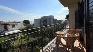Ein Balkon mit Korbmöbeln, Blick auf Gebäude und bewölkter Himmel.