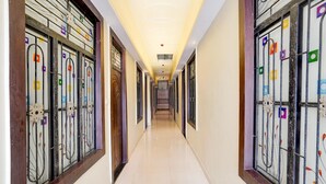 Un long couloir étroit doté d’un sol carrelé, de portes en verre décoratives de part et d’autre, et d’un plafond pourvu d’un éclairage encastré.