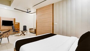 Une chambre d’hôtel moderne équipée d’un lit, d’un bureau, d’une chaise, d’une télévision et d’une armoire.