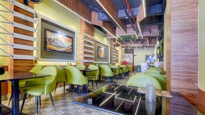 Un restaurant avec des chaises vertes, une table noire et un sol à motifs.