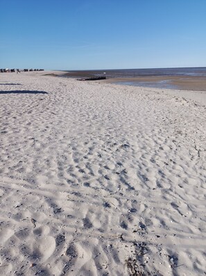 A sandy beach with footprints and a distant shoreline. - Detached Holiday Home Marlies Near the Beach for 4 Guests with 3 Bedrooms (Wangerland)