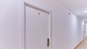 A hallway with a white door marked with the number 2, a light switch, and a wooden floor.