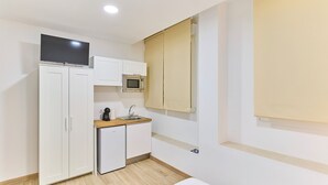A compact kitchen with white cabinets, a microwave, a coffee maker, and a small refrigerator.