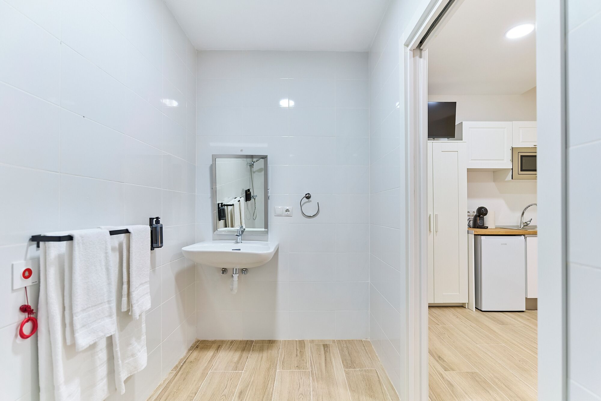 Un baño moderno con lavamanos, espejo y toallero.
