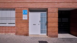 A brick building with a white door, a blue sign with 'CH' on it, and a barred window.