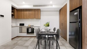 Una cocina moderna con comedor, que incluye un refrigerador negro, armarios blancos y una mesa de comedor preparada para cuatro.