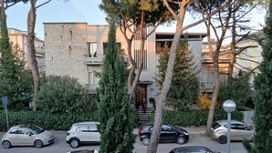 Un immeuble résidentiel au design moderne, avec des voitures garées et une végétation luxuriante tout autour.