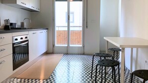 Une cuisine avec un carrelage à motifs, une cuisinière et une fenêtre avec des stores.