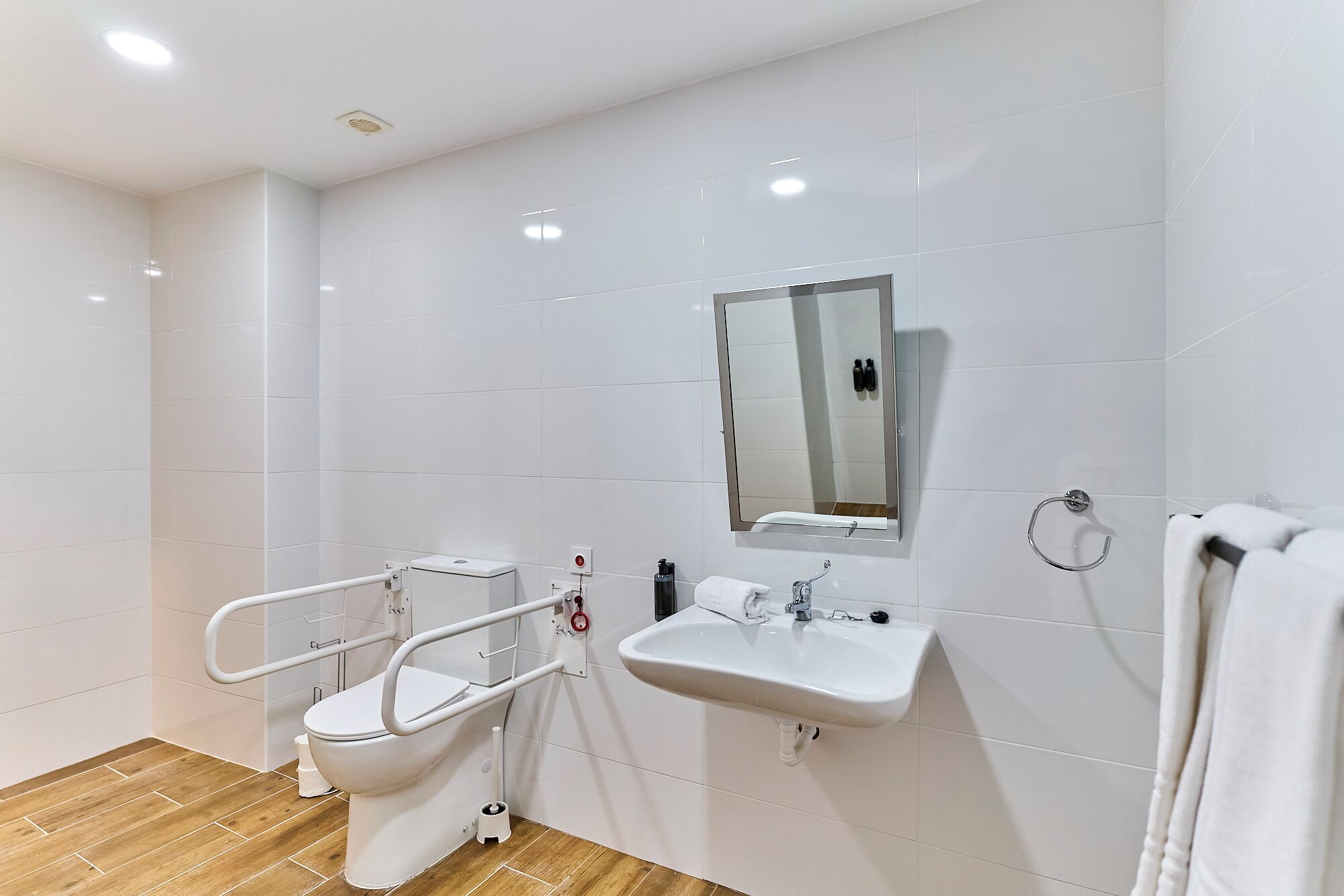 Un baño moderno con inodoro blanco, lavamanos y espejo.