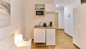 Cozinha compacta com micro-ondas, cafeteira e um pequeno armário.