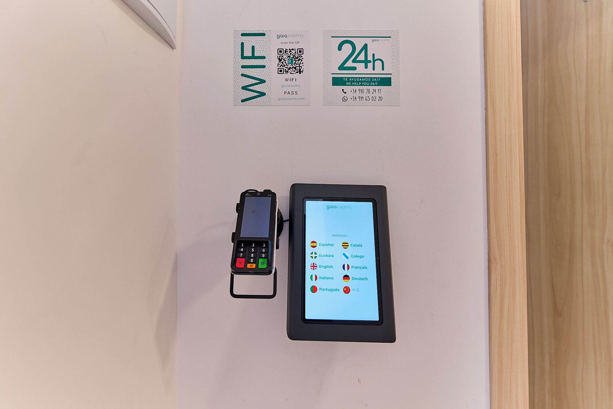 Een wifi-bordje, een bord dat 24-uurs service aangeeft, een QR-code en een digitaal apparaat met taalopties.