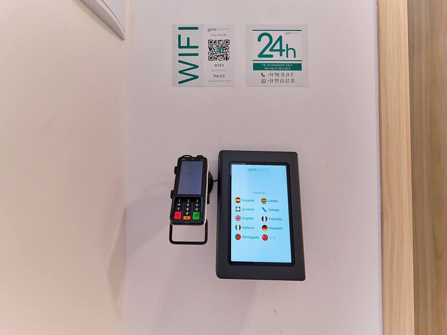 Een wifi-bordje, een bord dat 24-uurs service aangeeft, een QR-code en een digitaal apparaat met taalopties.