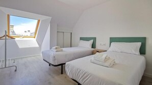 A room with two beds, a skylight, and a view of the cityscape. - Apartamentos Costa de Foz by gaiarooms  (Foz)