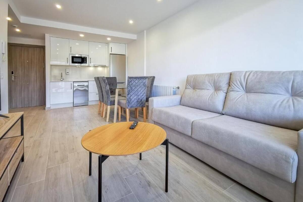 A modern living room with a sofa, a round coffee table, and a dining area with chairs and a table.