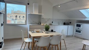 A modern kitchen with white cabinets, a marble backsplash, and a skylight. - Apartamentos Prior by gaiarooms (Salamanca)