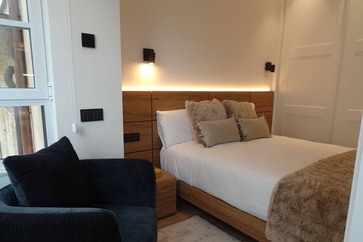 Une chambre à coucher avec un lit, des tables de chevet, une chaise et une petite table.