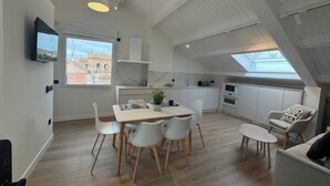 A modern kitchen with white cabinets, a dining area with a table and chairs, and a small seating area with a sofa and armchair. - Apartamentos Prior by gaiarooms (Salamanca)
