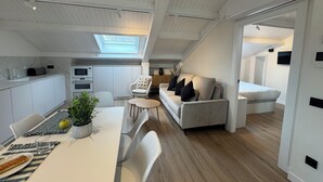 A modern kitchen with white cabinets, a dining table with chairs, a sofa, and a TV. - Apartamentos Prior by gaiarooms (Salamanca)
