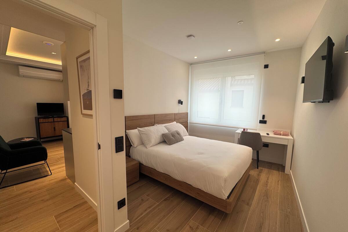 Une chambre à coucher moderne, équipée d’un lit, d’un bureau, d’une chaise, d’un téléviseur et d’une armoire.