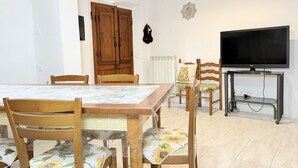 Un comedor con una mesa y sillas, un televisor sobre un mueble, y una puerta de madera.