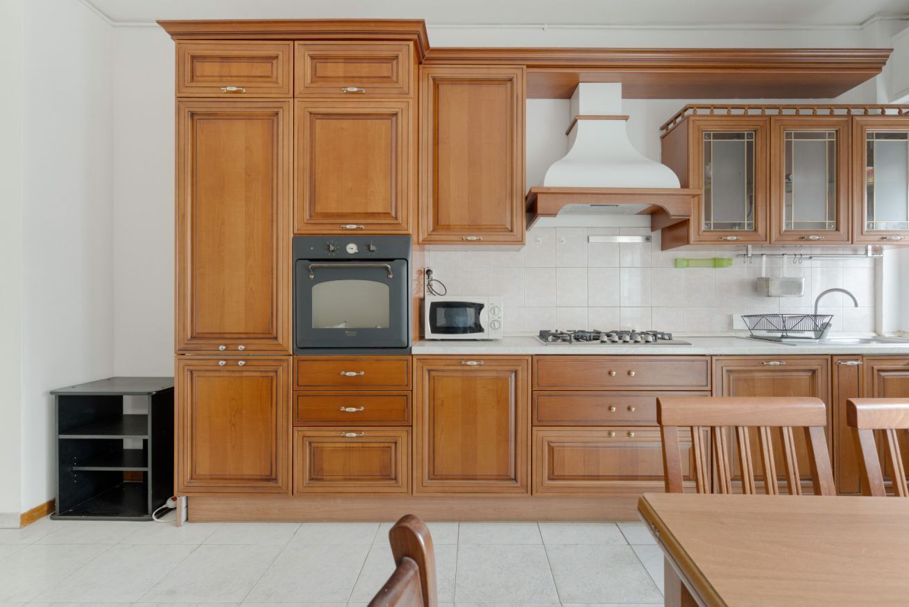 A kitchen with wooden cabinets, a stove, microwave, and a sink.