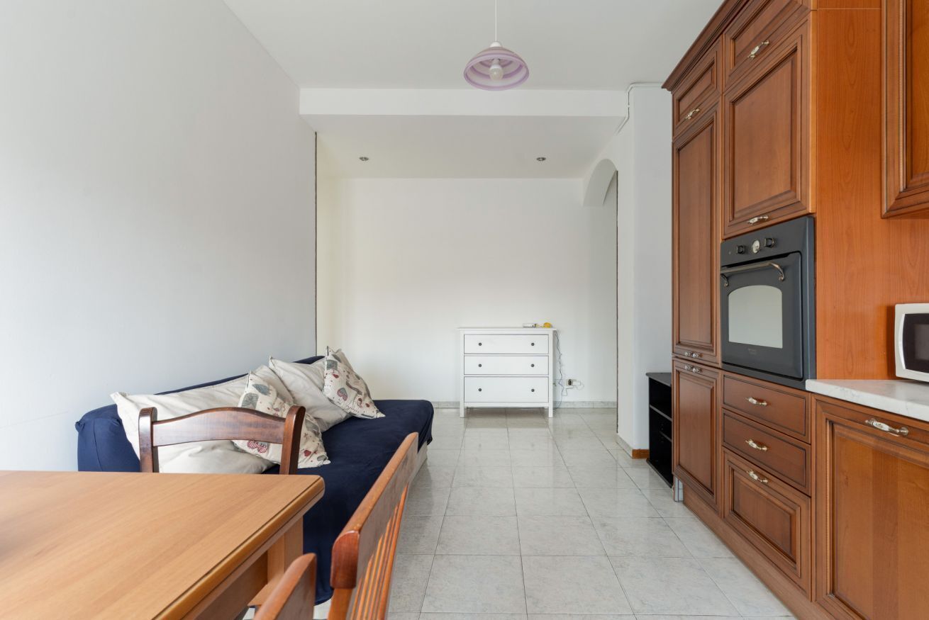 Una cocina compacta con armarios de madera, una encimera blanca y un horno empotrado.