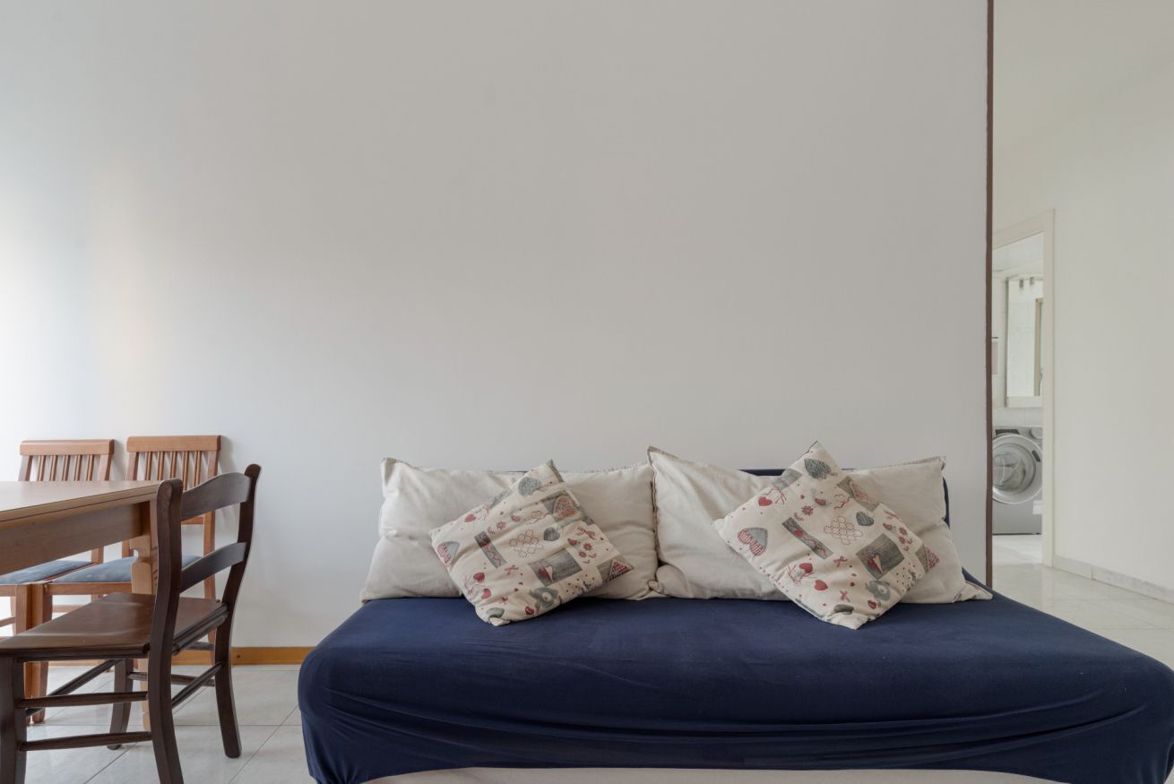 Una camera da letto con un letto, due cuscini, una sedia di legno e un tavolino.