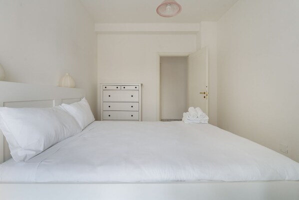 A bedroom with a bed, a dresser, and a door leading to another room. - Cozy 60m2 apartment, ideal for 4 people, located on the third floor of a building with lift.The accommodation is located a stone's throw from the Lambrate stop of the Green Metro Line and the train station of the same name.In 10 minutes by car you can  (Milan)