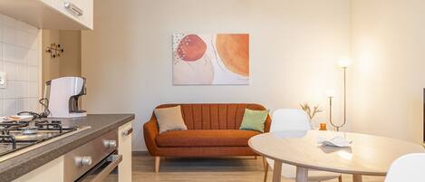 A modern kitchen with a gas stove, a sofa, and a dining table with chairs.