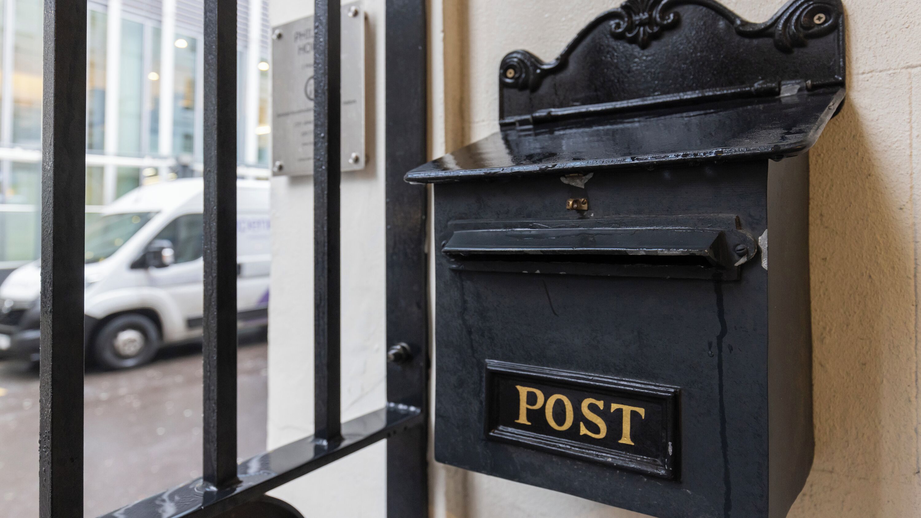 Ένα μαύρο γραμματοκιβώτιο με τη λέξη «POST» γραμμένη πάνω του, τοποθετημένο σε έναν τοίχο.