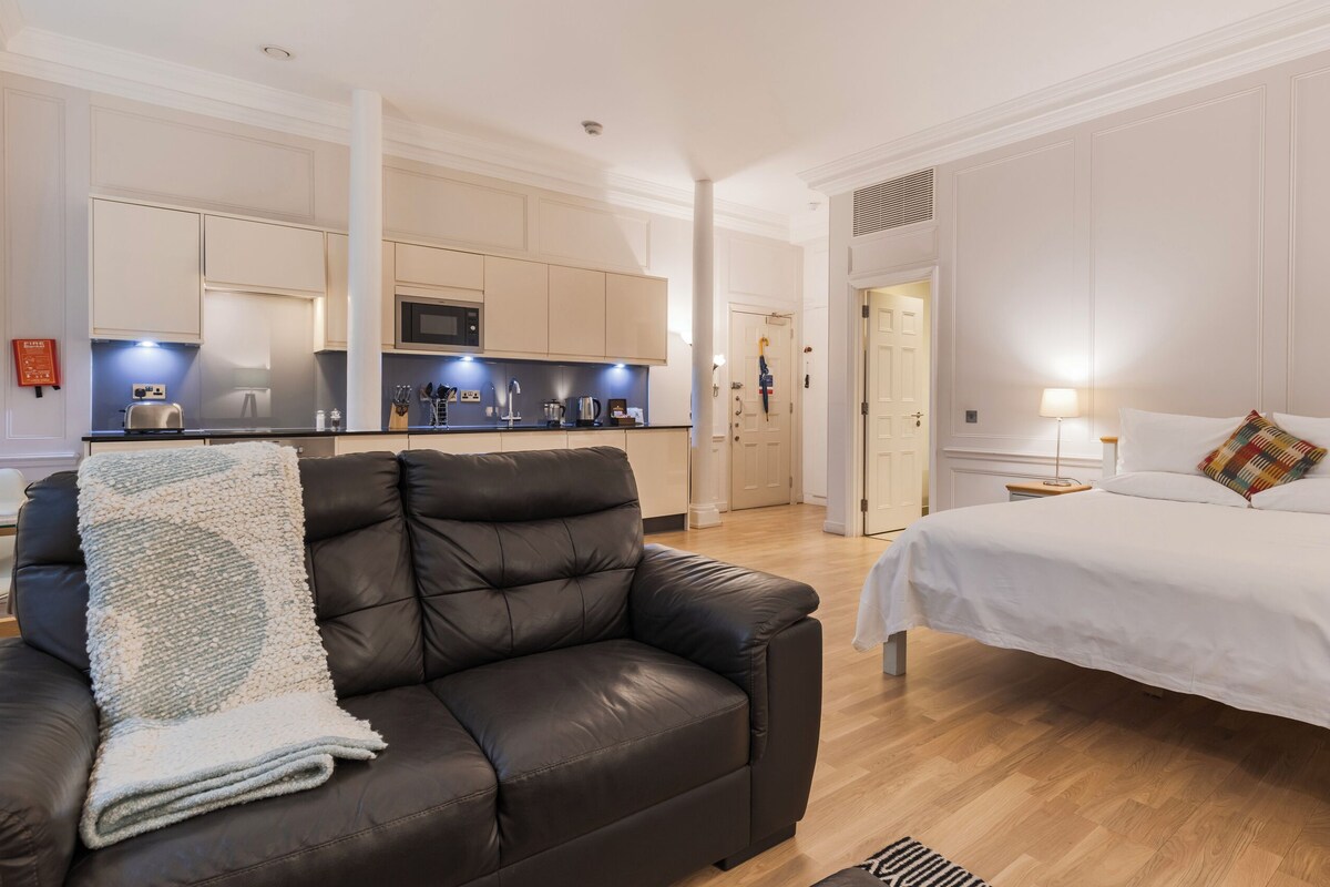 Ein Hotelzimmer mit Bett, Ledersessel, Küchenzeile und Bad.