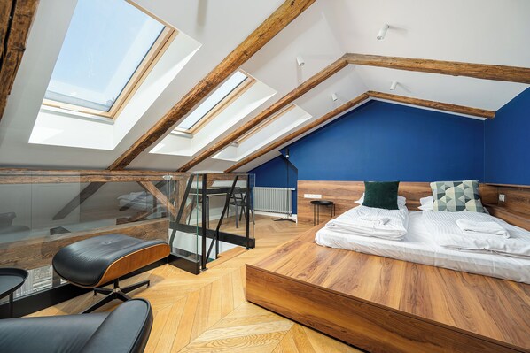 A modern loft bedroom with skylights, a bed, a desk, and a chair. - RentPlanet - Piotrkowska (Łódź)