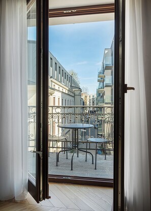 An open balcony with a metal railing, a round table, and two chairs. - RentPlanet - Piotrkowska (Łódź)
