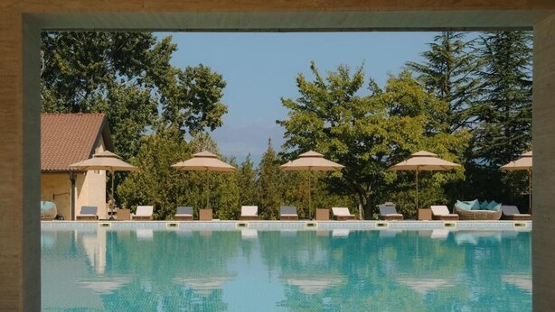 A swimming pool with lounge chairs and umbrellas, surrounded by trees. - Hotel Meteo Kakheti (Telavi)