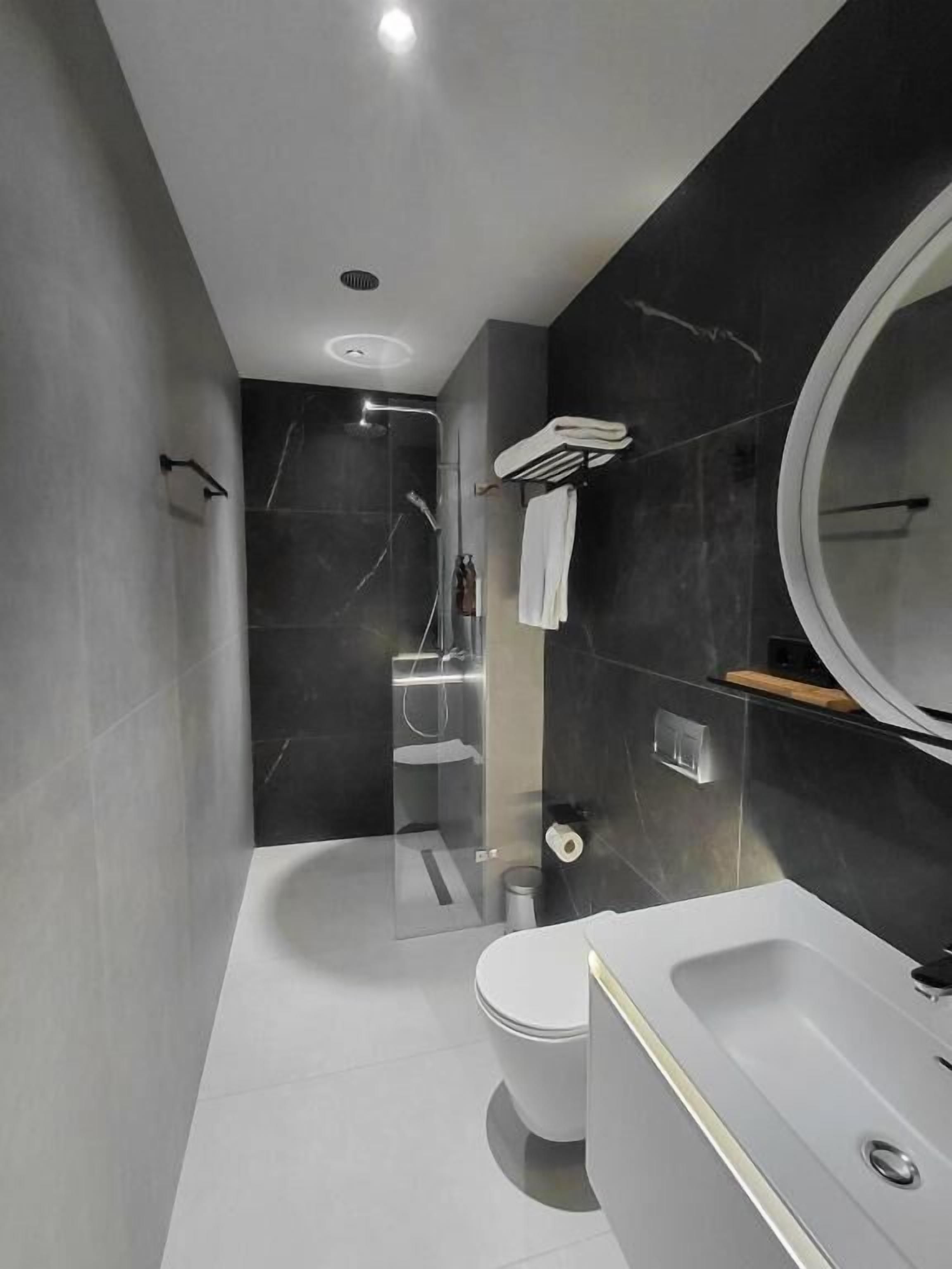 Een moderne badkamer met bad, toilet en douche.