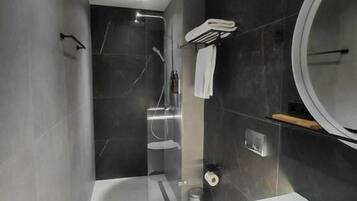 Een moderne badkamer met bad, toilet en douche.