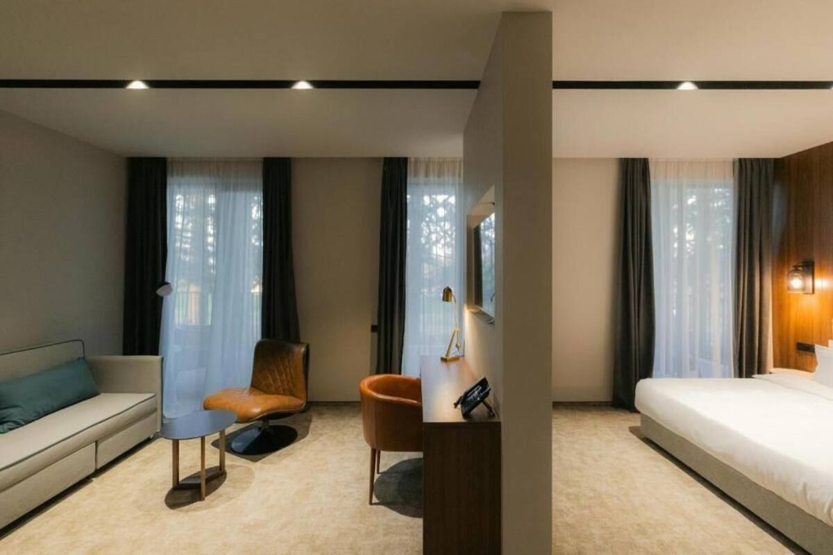 Una habitación de hotel con una cama, un sofá, una silla y un escritorio con una lámpara.