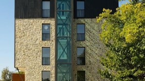 A modern building with a stone facade, multiple windows, and a central glass elevator shaft. - Hotel Meteo Kakheti (Telavi)