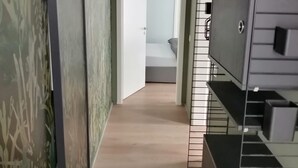 Een gang met een deur naar een badkamer, een trap en een aan de muur bevestigde televisie.